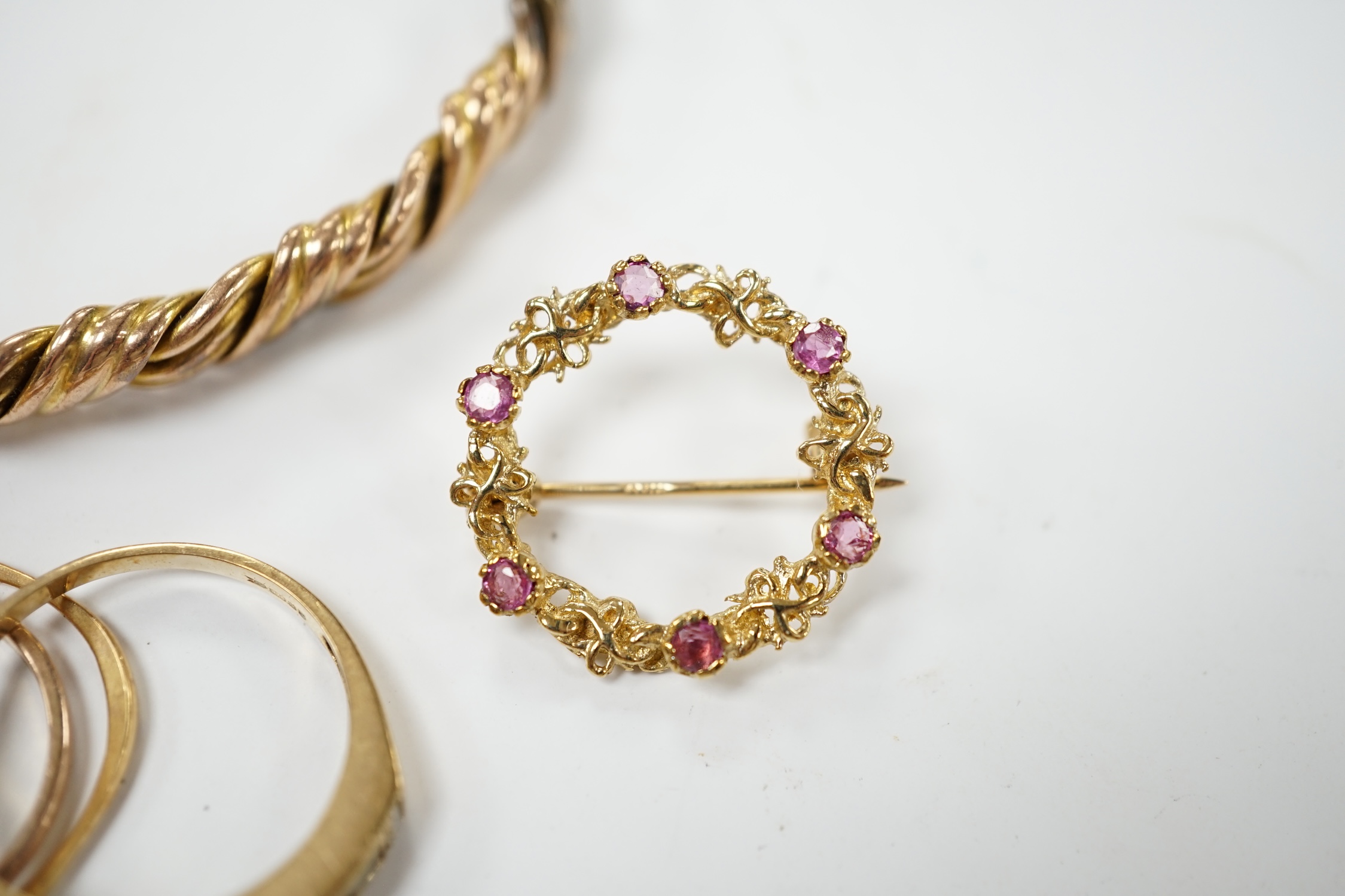 An early 20th century 9ct hinged bangle, three assorted 9ct gold rings and a modern 9ct gold and gem set brooch and two other yellow metal rings, gross weight 23.2 grams. Condition - poor